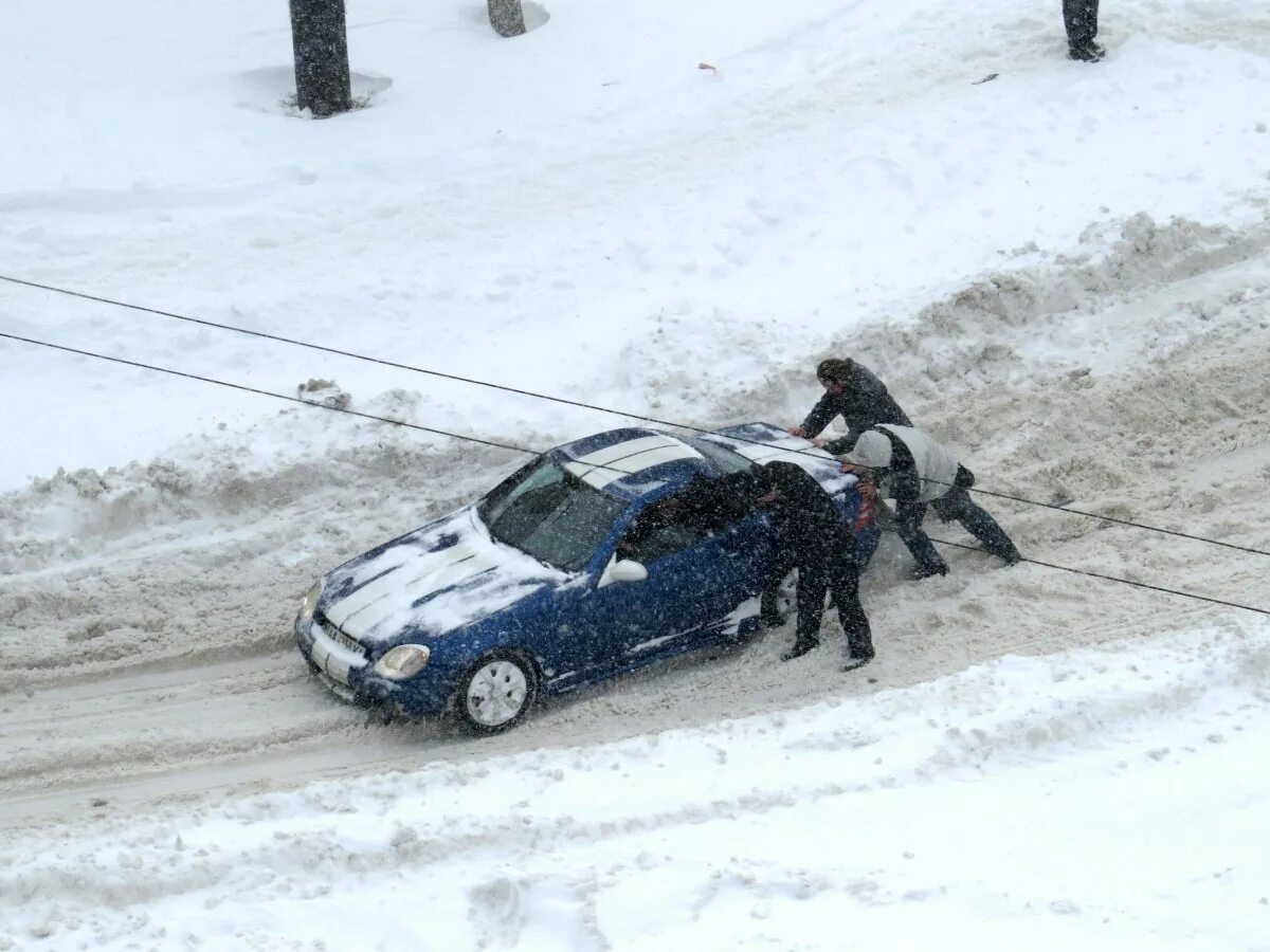 Застревают в сугробах. Толкают машину в снегу. Выталкивать из сугроба машину. Толкают машину из сугроба. Машина застряла в снегу.
