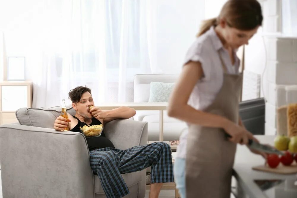 Пока муж смотрит телевизор жена. Уставшая жена на кухне с мужем. Муж на диване жена на кухне. Ленивый муж и жена. Жена готовит муж на диване.