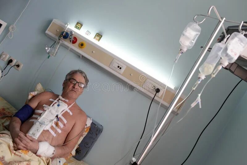 Давай в больнице после операции. Пациент с капельницей в больнице. человек лежит под капельницей.