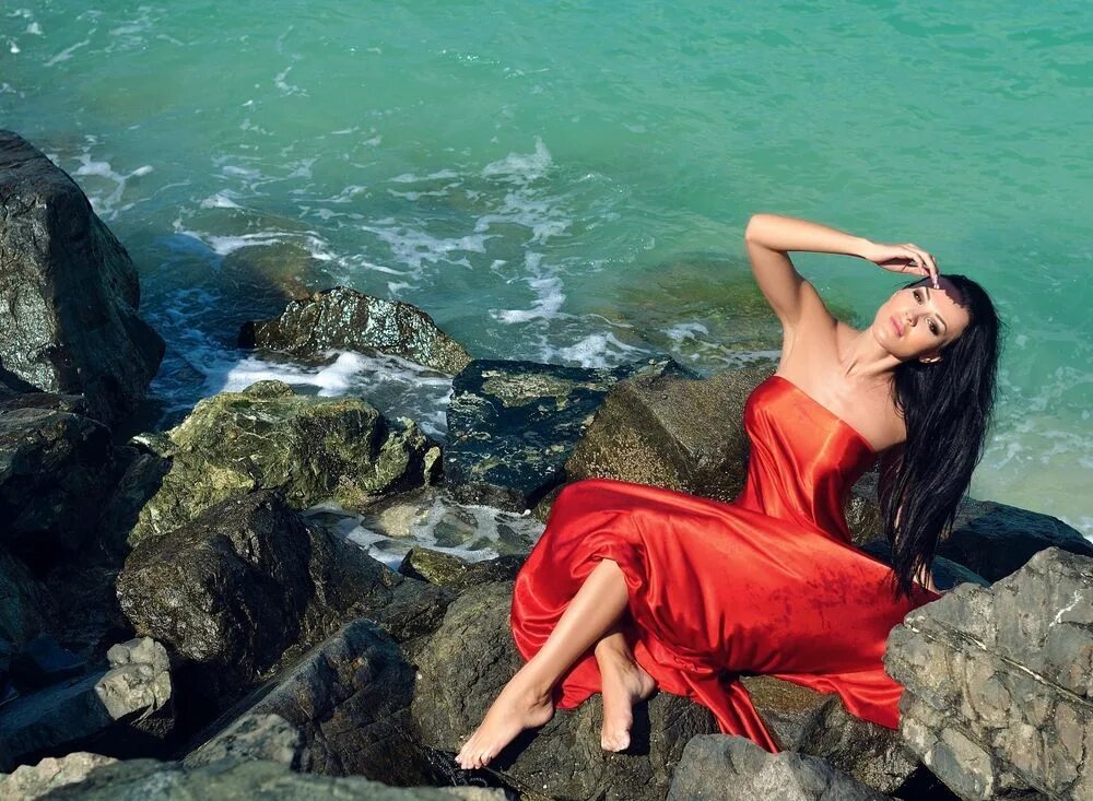 Видео жены брюнетки. Девушка в Красном на море. Девушка платье на море сидит. Девушка в Красном платье на море на Камне. Девушка брюнетка в Красном платье сбоку на море.