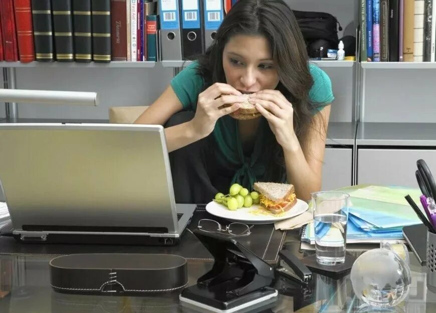 Запрет есть на рабочем месте. Перекус в офисе. Человек ест за компьютером. Человек перед компьютером. Девушка перекус.