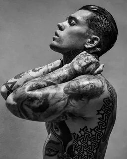 a black and white photo of a man with tattoos.