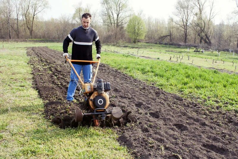 Паханное поле. Вспашка огорода трактором. Мужчина с культиватором. Машина которая вспахивает землю. Когда пахать землю весной