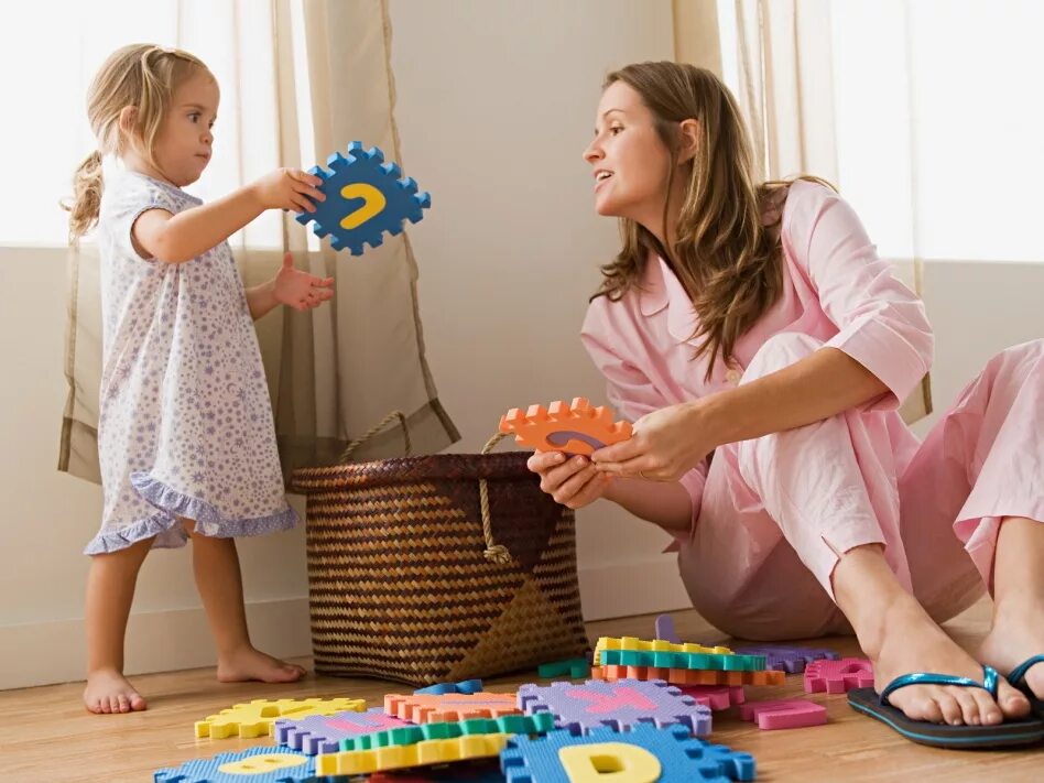 Ребенок убирает игрушки. Ребенок собирает игрушки. Дети играют дома. Мама дает ребенку игрушку.