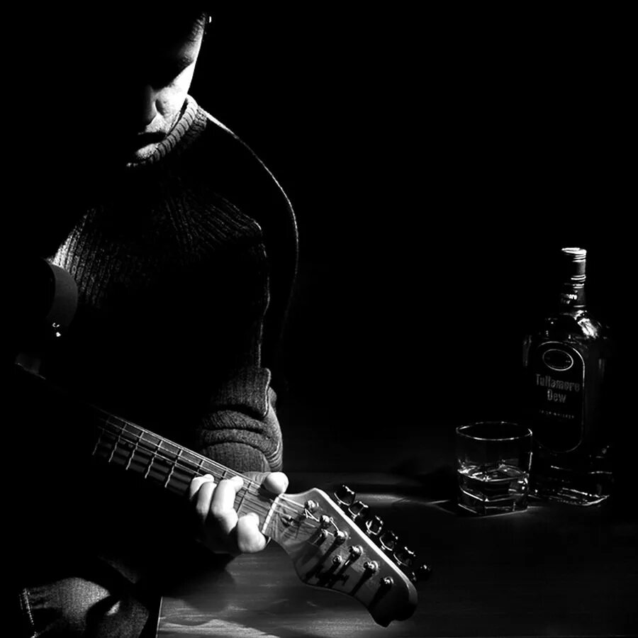 Парень с гитарой. С гитарой в темноте. Гитарист на черном фоне. Грустный гитарист.
