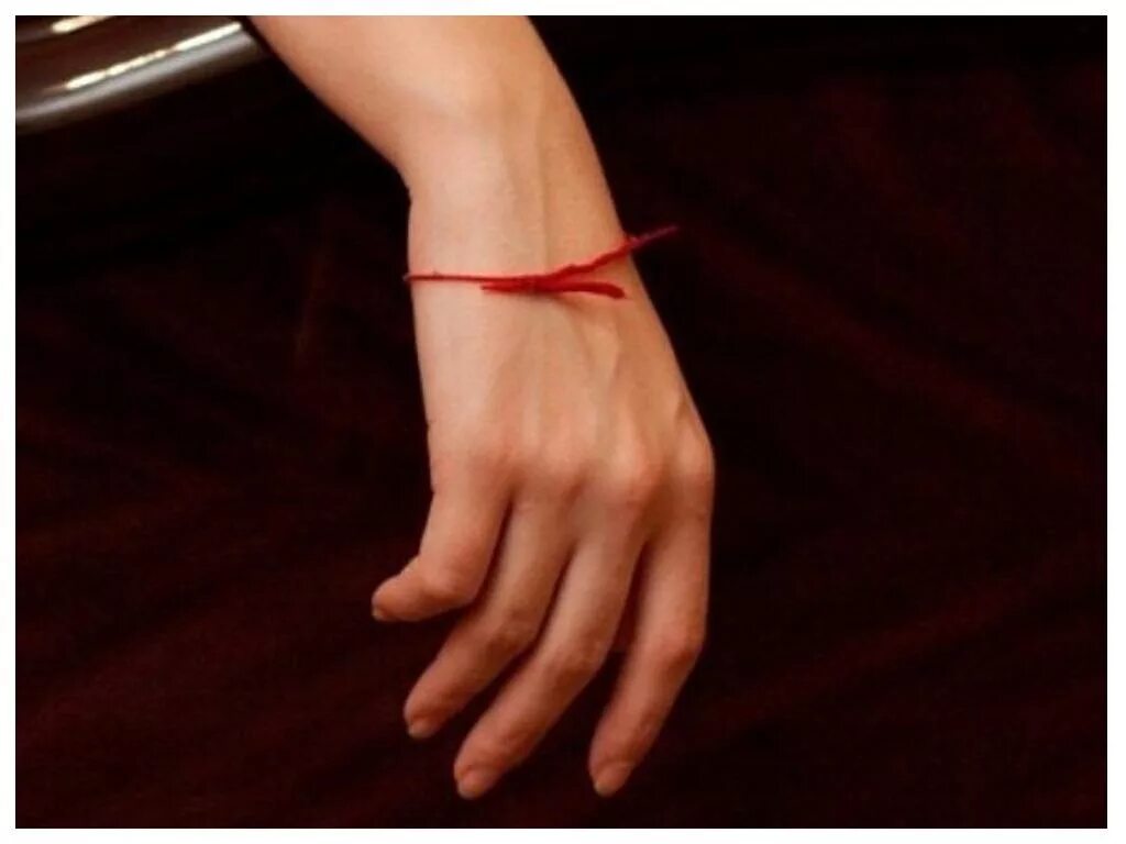Красная лента на руке. Красная нитка на запястье. Красная нить на руке.