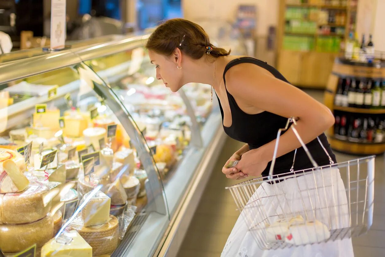 Невкусный магазин. Покупатель сыра. Женщина выбирает сыр в супермаркете. Покупатель выбирает сыр. Женщина в супермаркете.