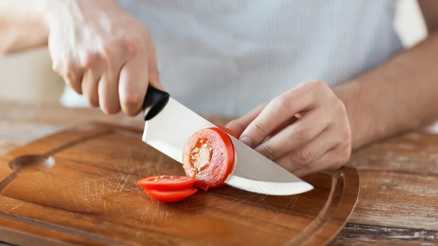 Разделочная доска с порезами. Разделочная доска с ножом. Нож режет овощи