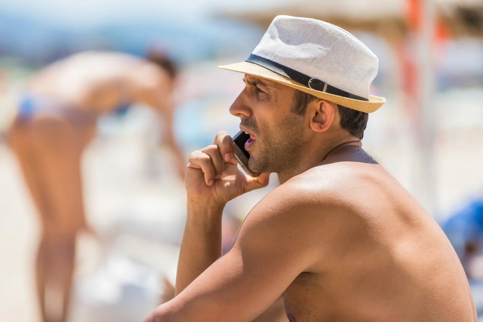 Мужчина на берегу моря с ноутбуком. Парень лежит на пляже. Человек на берегу океана. Мужик в шляпе на пляже. Парень смотрит на пляже.