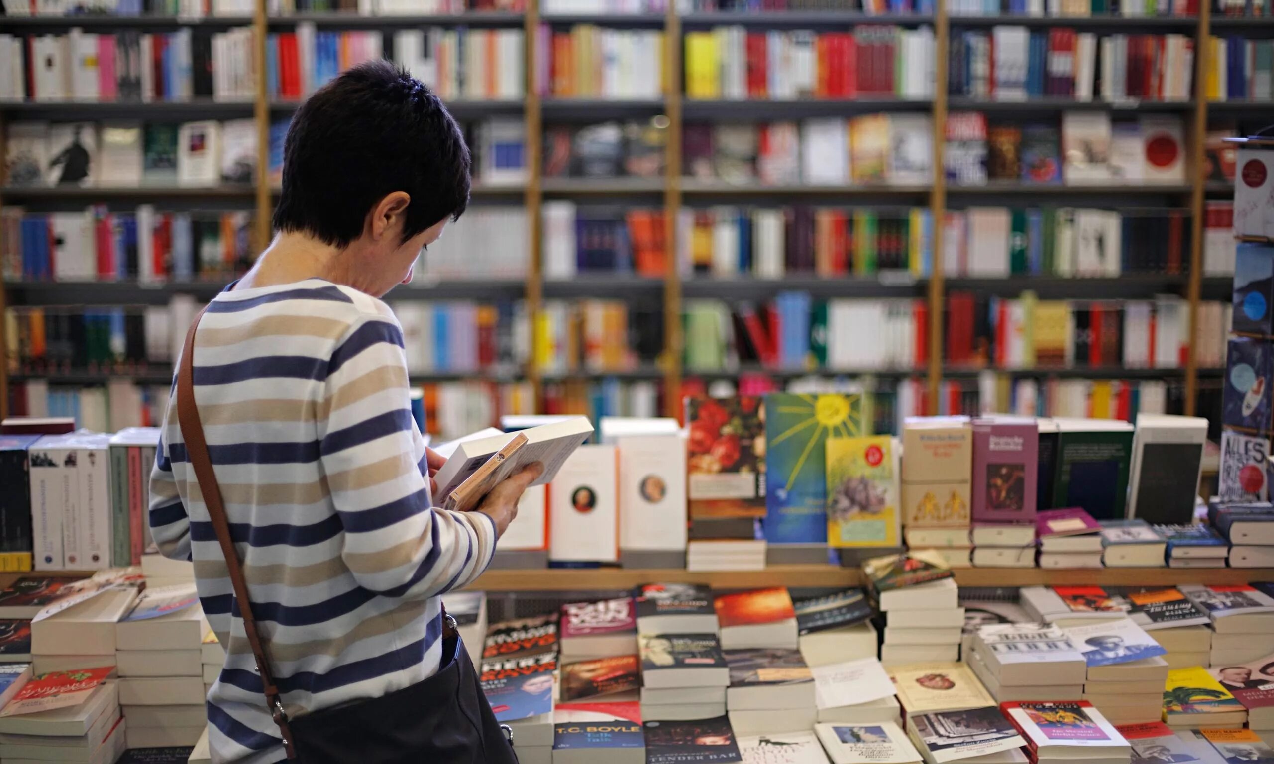 Люди в книжном магазине. Покупатели в книжном магазине. Книжный прилавок. Чтение книг в книжном магазине.