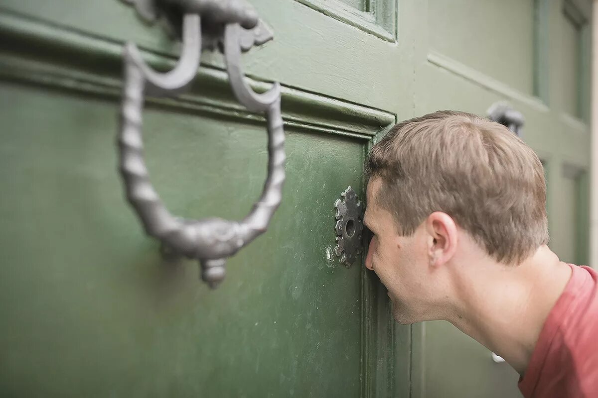 Заглядывает в замочную скважину. Человек подсматривает. Подглядывание комната