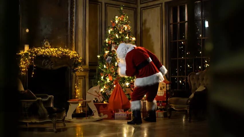 Santa putting presents under the Christmas Tree. Falling in Love at Christmas (secretly Santa).