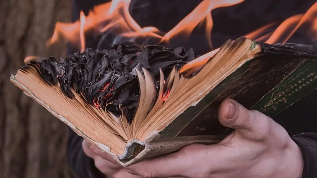 Человек сжигающий книги. Книга с огнем. Человек сжигающий книги. Горящая книга в руках. Роман брэдбери 451 градус по фаренгейту.