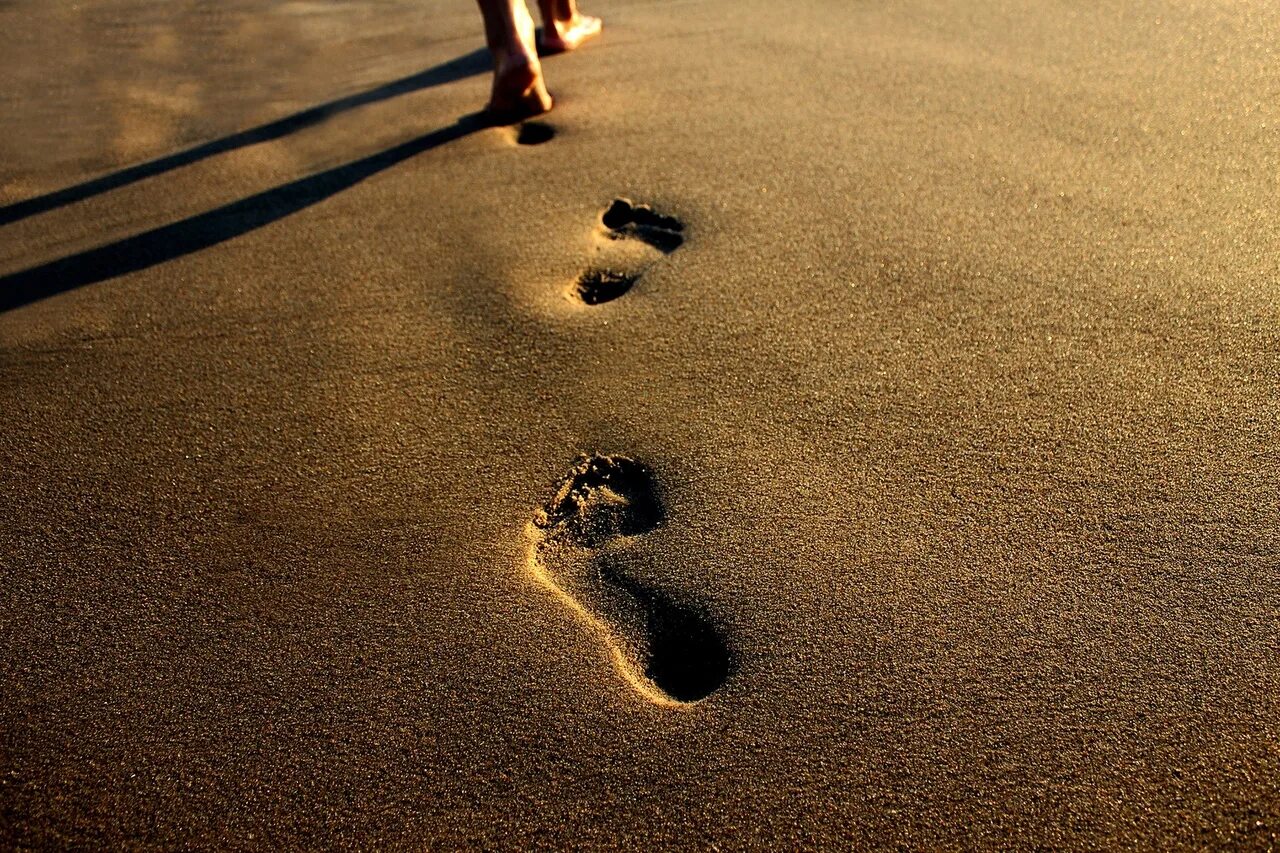 По земле идет большой. Следы на песке. Следы человека на песке. След человека на земле. Следы на песке у моря.