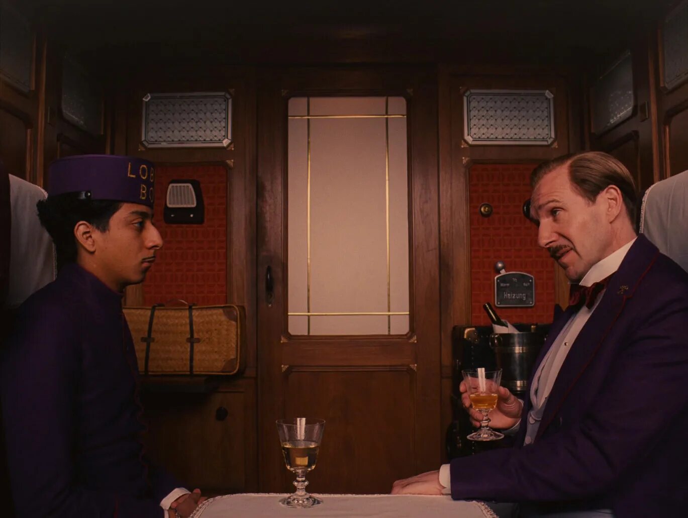 Стойка портье в гостинице. Джейсон шварцман отель гранд будапешт. Рэйф файнс отель гранд будапешт. Портье трейлер. Французский актер портье.
