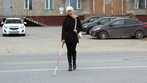Человек с белой тростью держит ее горизонтально