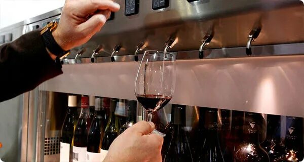бокал за стойкой бара. вино с краном. аэратор для вина. вино на разлив. утечка вина.