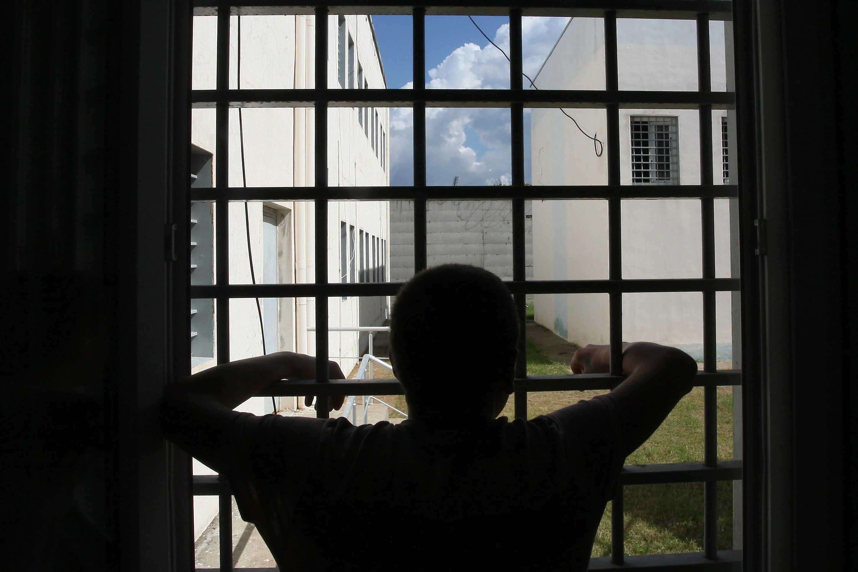 одинокий человек в комнате. сидит у окна. парень на подоконнике. бывший сидит под окнами. вид из тюремного окна.