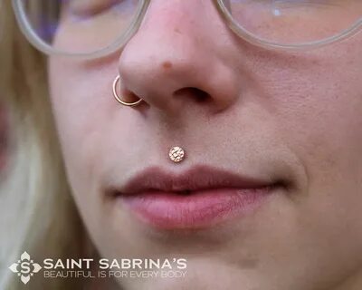 a close up of a person wearing glasses with a nose ring on her nose and the...