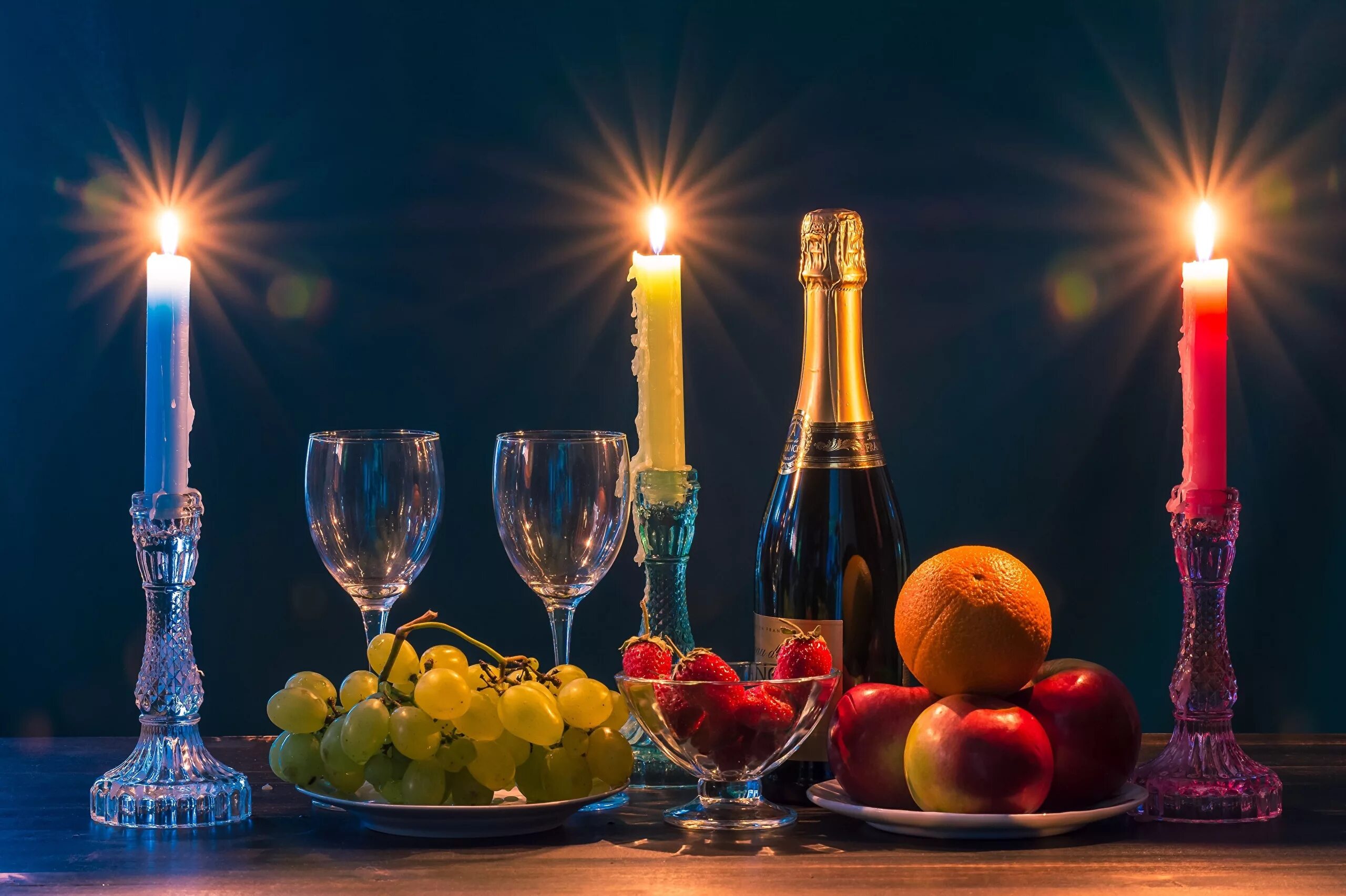Шампанское и свечи. Натюрморт. Бокалы шампанское со свечами. Стол с шампанским и фруктами.