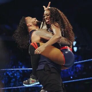 a man is holding a woman on his back in the middle of a wrestling ring.