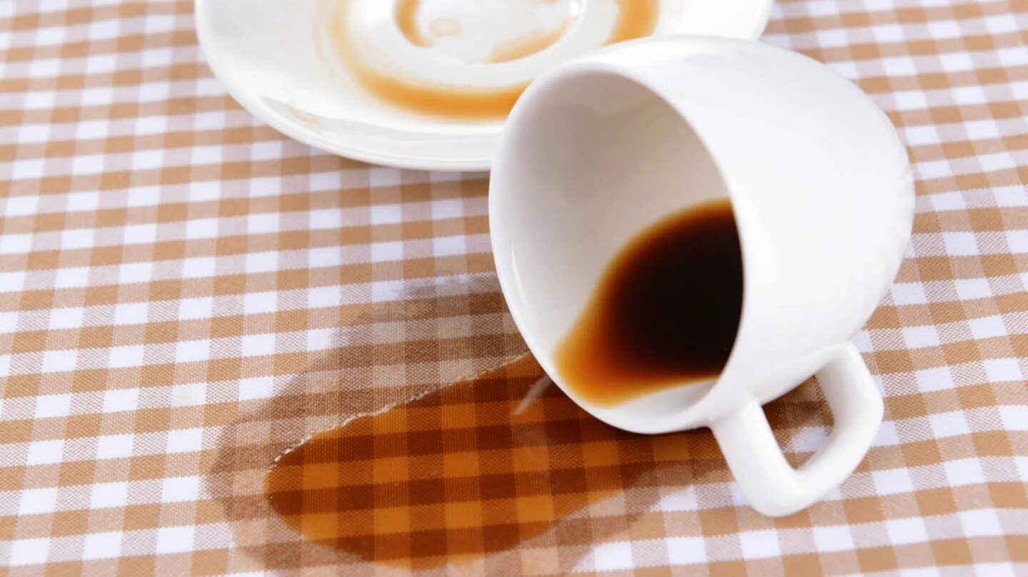 Пятна от чая. Разлитая чашка кофе на столе. Кружка лежит на столе. Опрокинутая чашка. Кофе на скатерти и чашка.