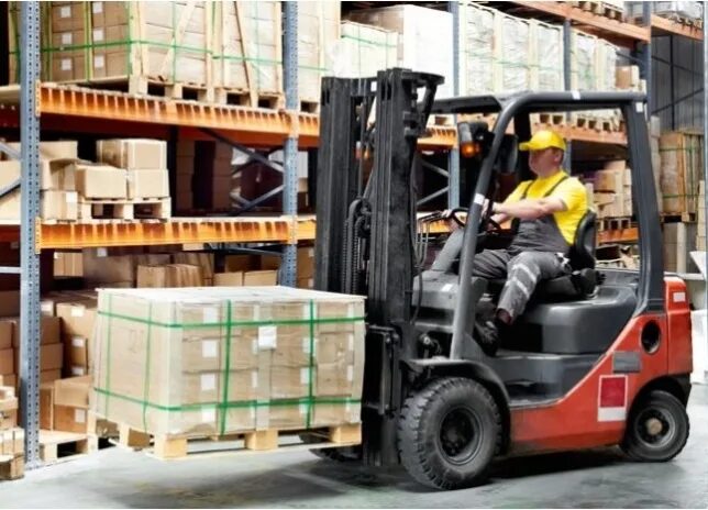 Погрузка поддонов на складе. Склад с коробками. Везем со склада. Выгрузка коробок. Рабочий склада.