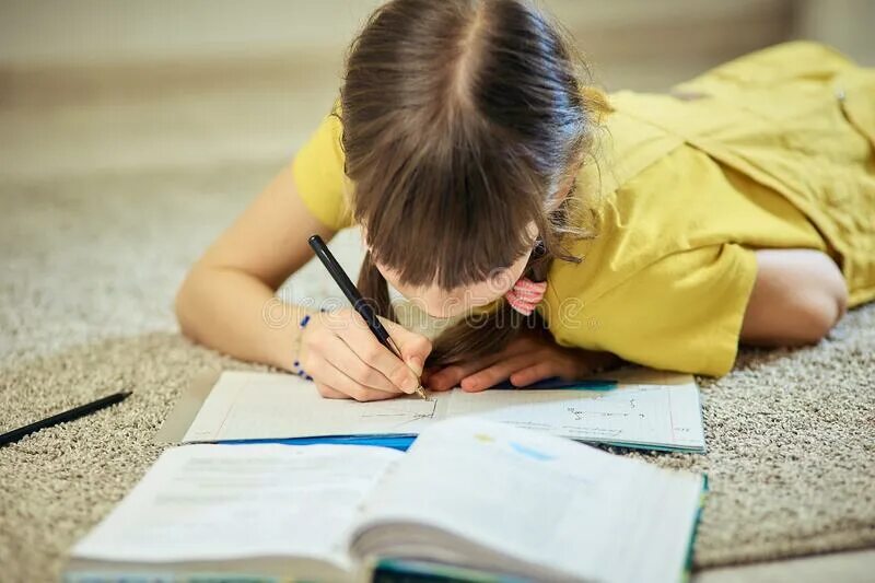 Маленькая девочка делает уроки. Девушка лежит на ковре делает домашнюю работу. Девушка делает уроки на улице. Девушки на карантине рисунок. Girl is doing her homework.