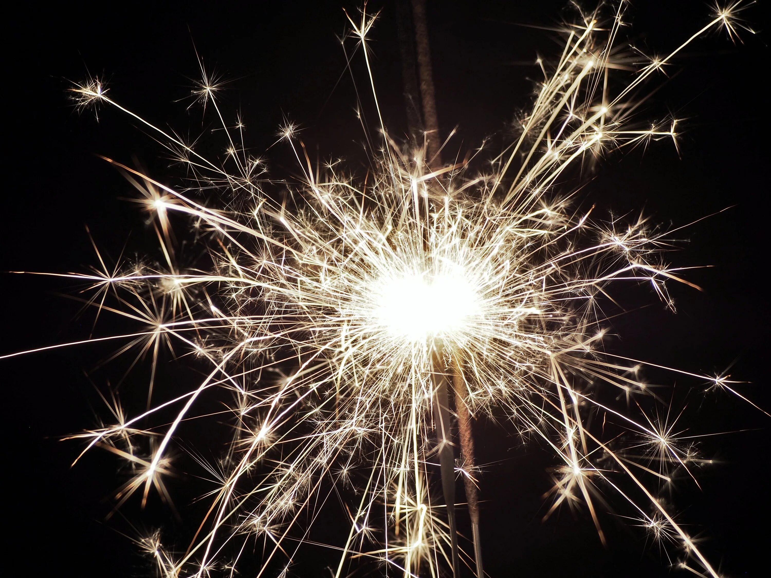 Рука в варежке держит бенгальский огонь. Зеленый фейерверк. Разноцветные бенгальские огни. Фейерверк на зеленом фоне. Зеленые бенгальские огни.