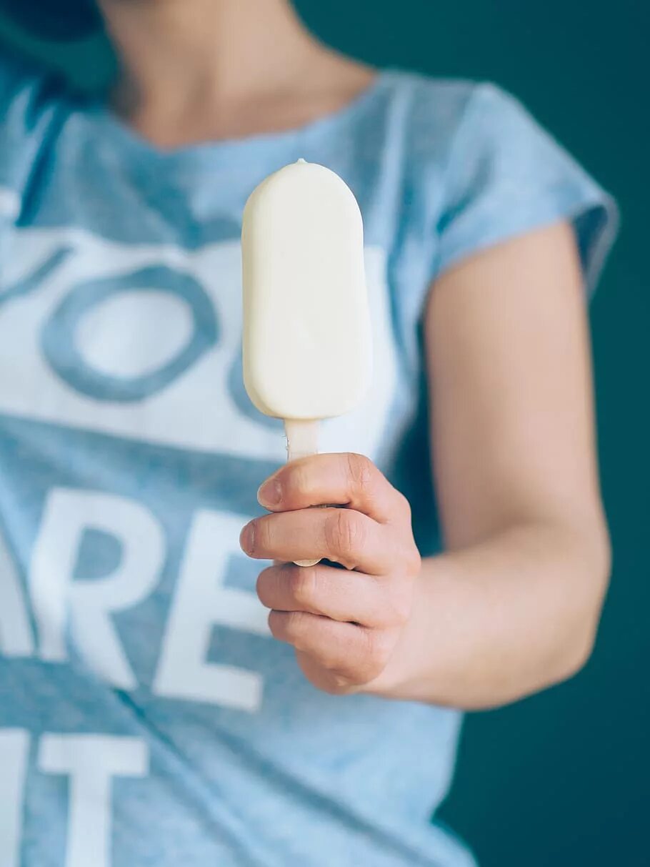Мороженое на палочке в руке. Мороженое на палочкемв руке. Рука держит мороженое. Пломбир на палочке в руке.
