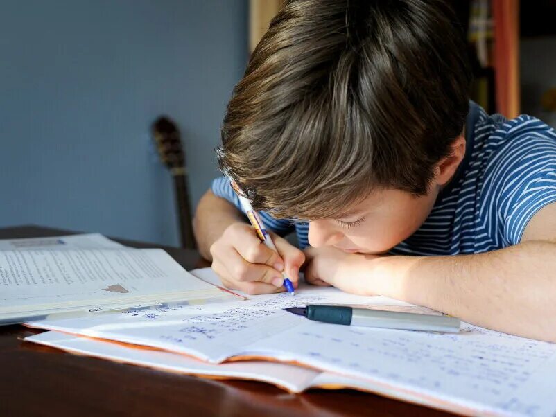Ученик пишет в тетради. Ребенок пишет. Дети записывают дом задание. Первоклассник пишет в тетради.