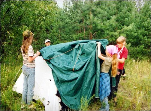 Дети устанавливают палатку. В походе дети раскладывали палатку. Родители с детьми в походе. Дети в туристской палатке.