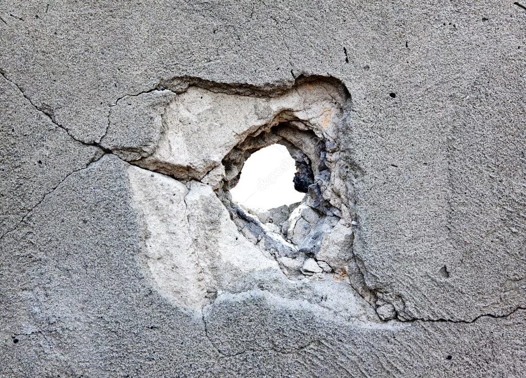 В стене дыра в дыре глаза. Дырка в стене. Дыра в бетонной стене. Разрушенный бетон. Трещины в бетоне.