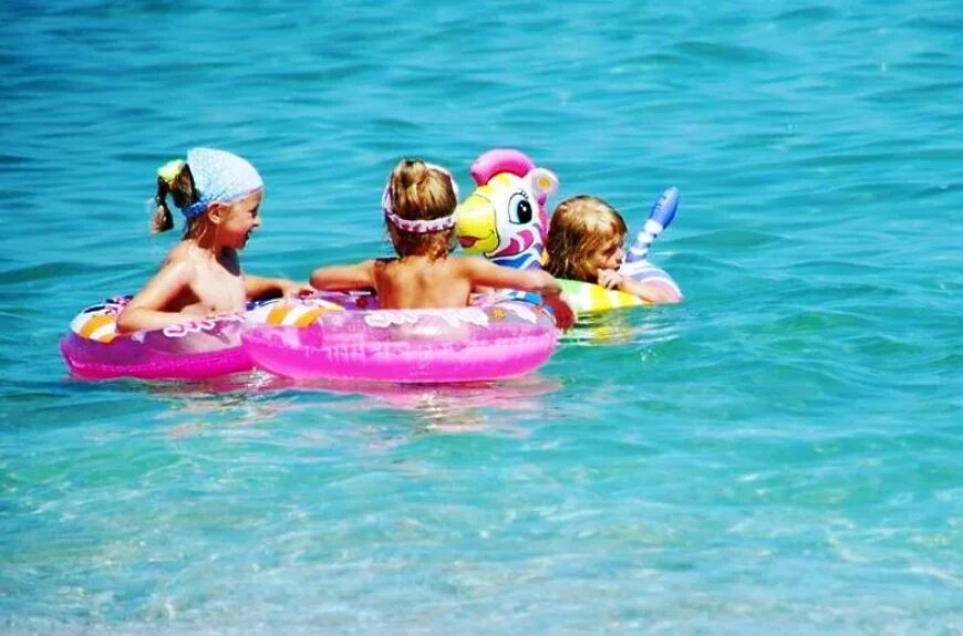 Дети купаются в море. Дети на море. Малыш на пляже. Дети с кругом на море.