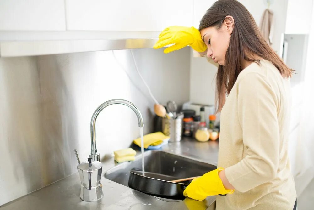 Мытье сковороды. Женщина моет посуду. Мойка посуды. Уборка кухни. Женщина моющая посуду.