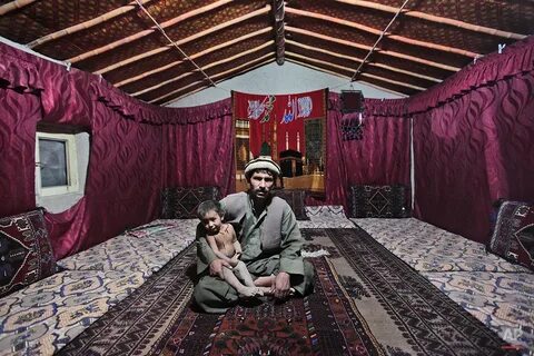 an Afghan man holds his son Ameer Ahmed as they poses for picture inside th...