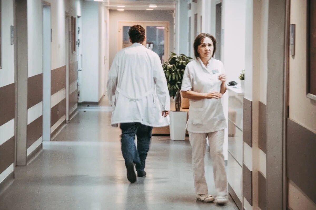 Пациенты сидят в очереди к врачу. Врач идет по коридору. Идти к врачу больницы. Прием терапевта. Больница коридор врачи.