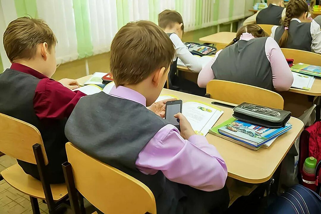 Как найти телефон в школе. Школьники на уроке. школьник с телефоном на уроке. школьники в гаджетах в школе. школьники сидят на уроке.