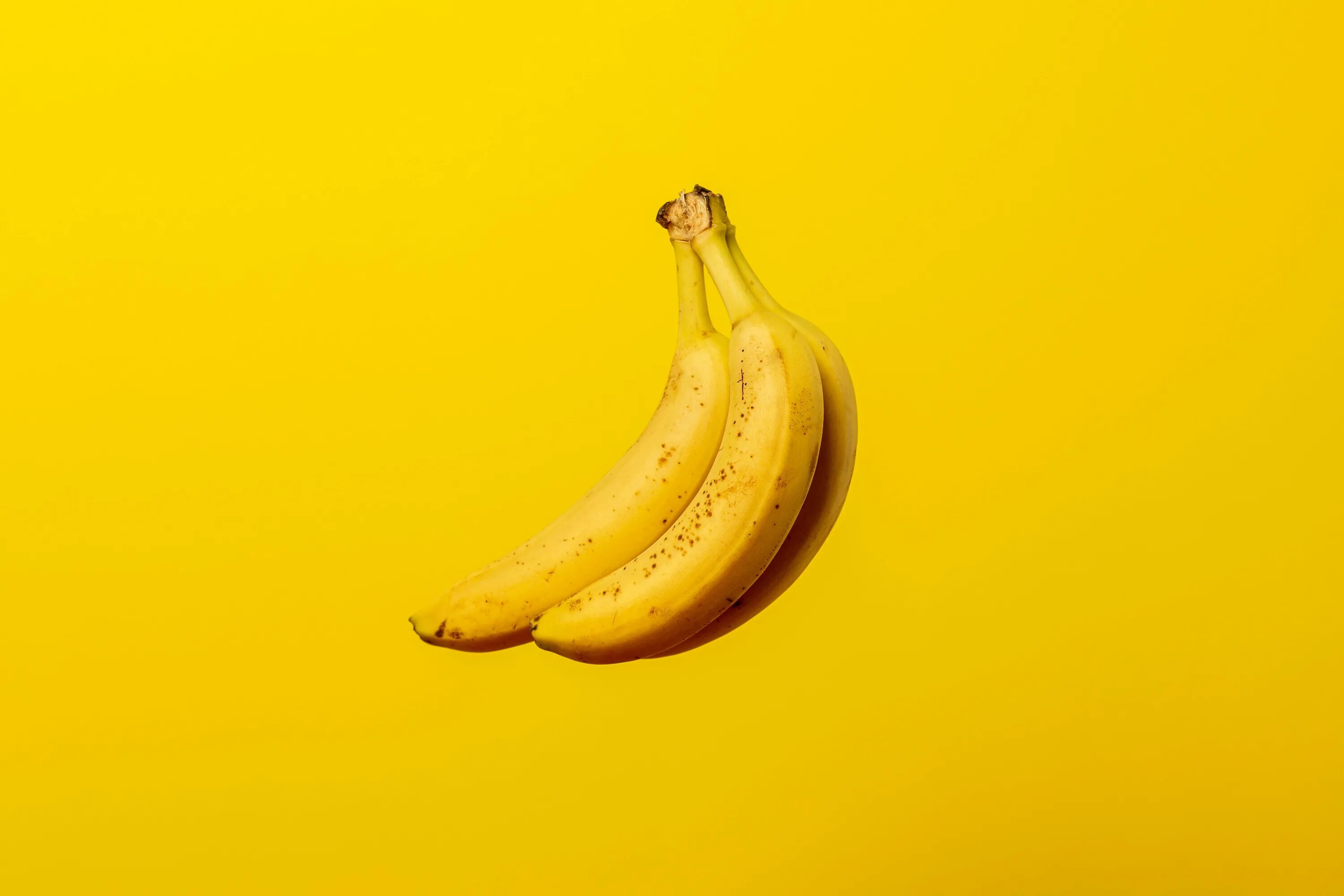 Бананчики. Обои с бананами. Желтый банан. Бананы фон. Банан на желтом фоне.