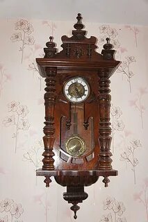 Старинные настенные часы с маятником в деревянном корпусе.