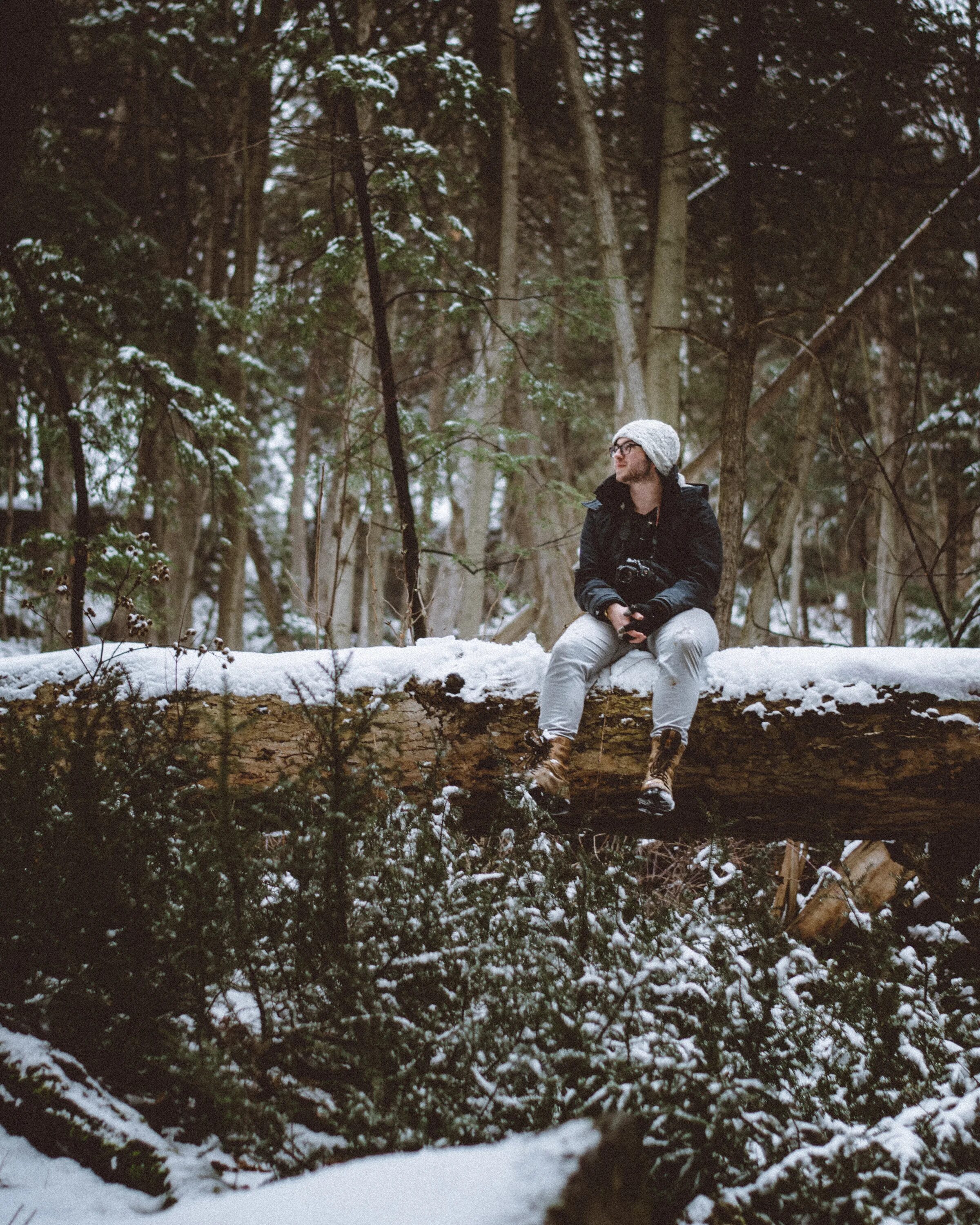 Среди серых еще не одетых деревьев. Фотосессия в лесу. Фотосессия в лесу зимой. Человек в заснеженном лесу. Парень в лесу.