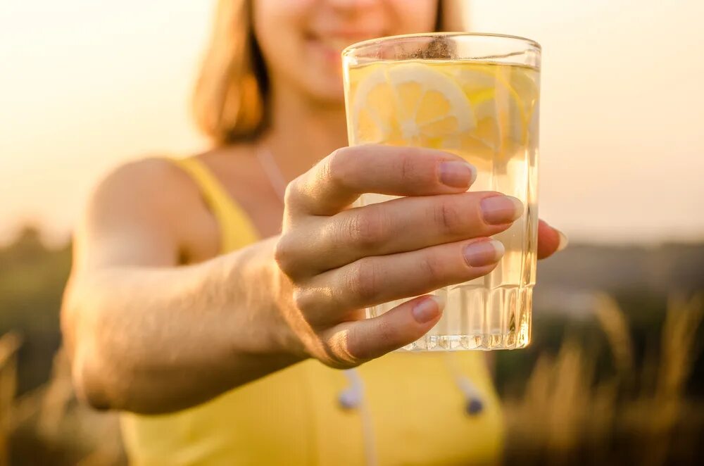 Стакан воды с медом. Стакан воды с лимоном. Лимонад в руке. Медовая вода.