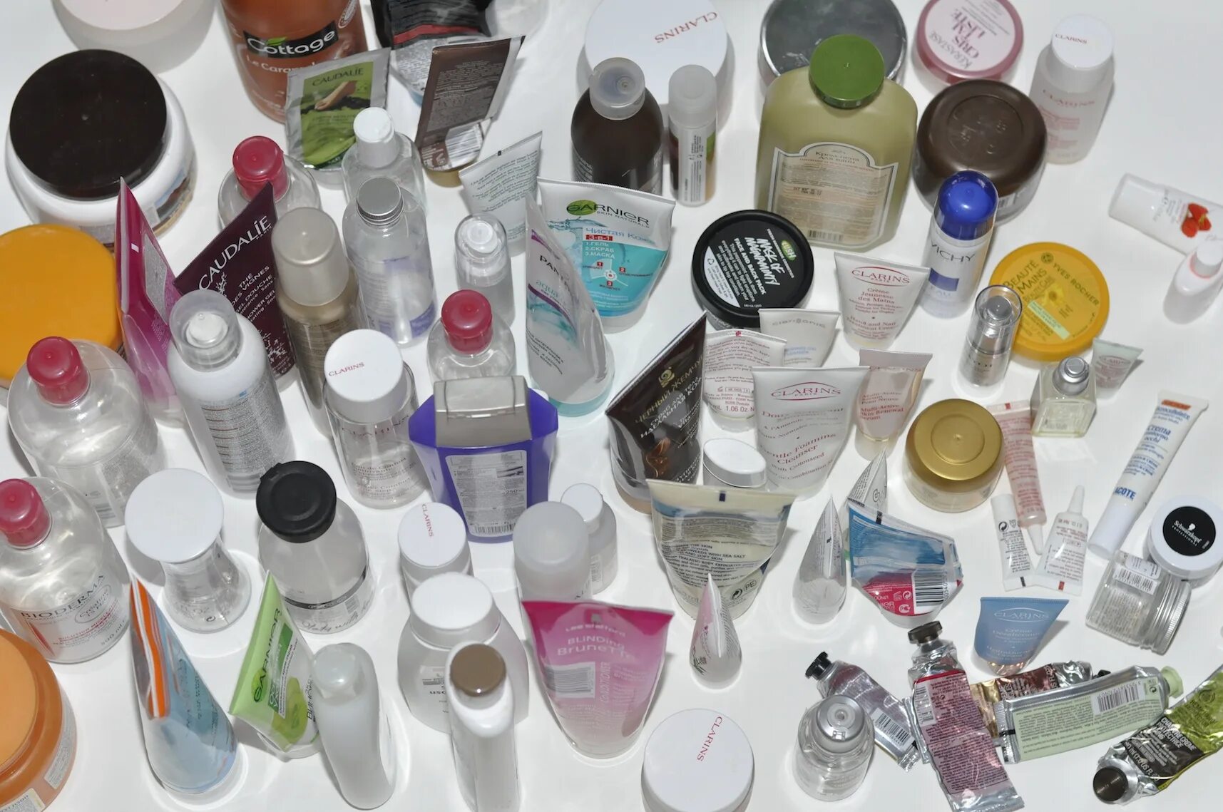 Очень много крема. Очень много крема. Девушка и уходовая косметика. Уходовые средства для лица. Много баночек с кремами.