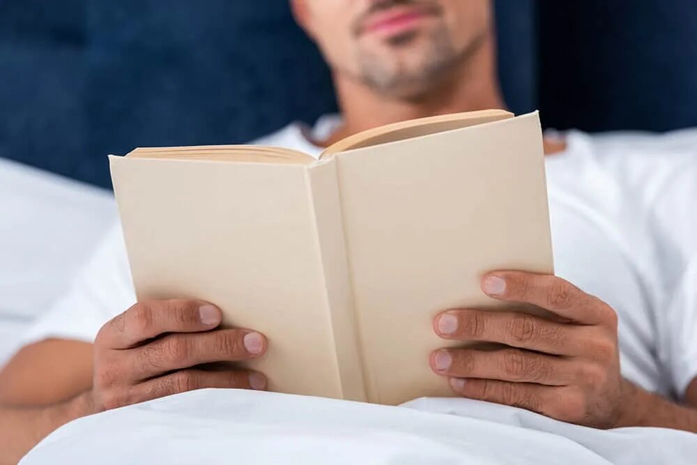 Книга лежит в шкафу. Мужчина читает на кровати. Книга лежит. Человек лежит с книгой. Парень лежит на книгах.
