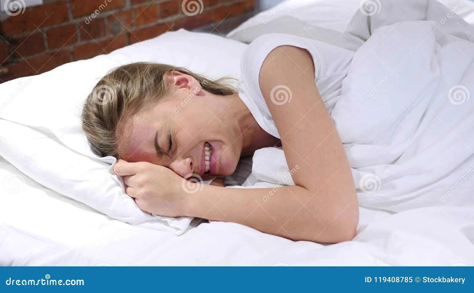 Плач в подушку. Женщина лежит в постели. Плачет в подушку.