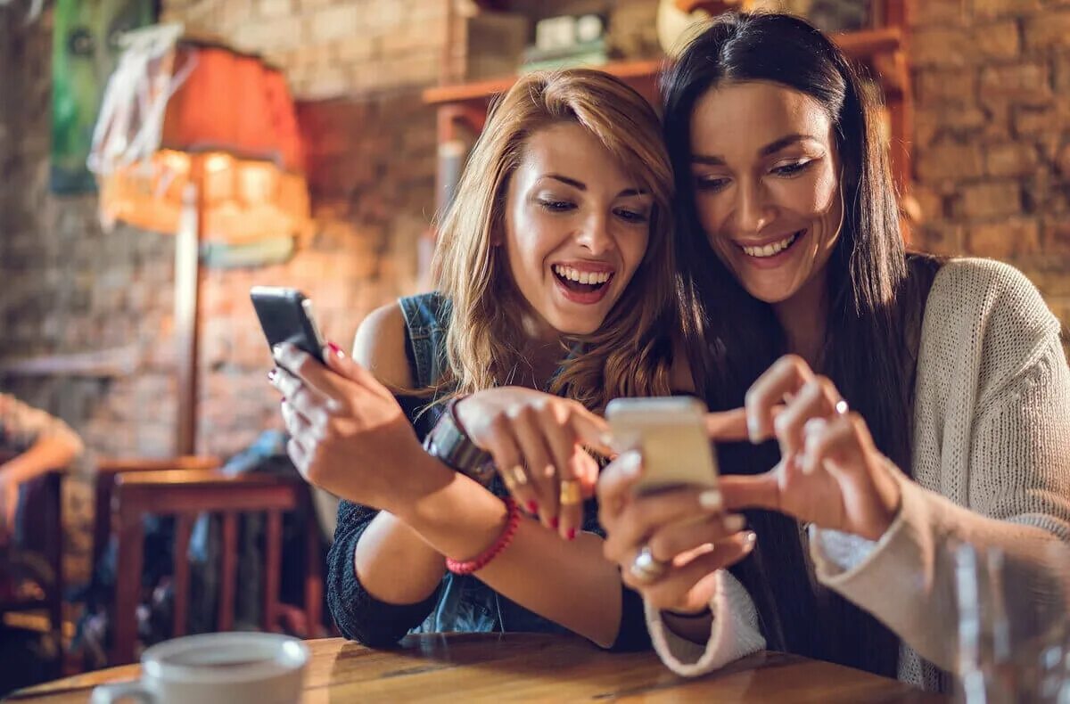 Use your friends. Подруги в кафе смеются. Девушка смеется. Девушка с друзьями в кафе. Девушка со смартфоном.