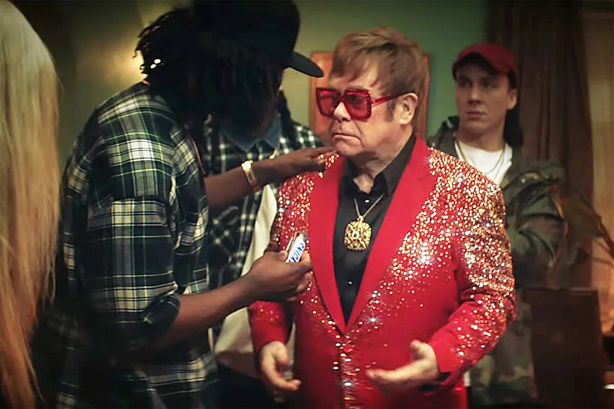 Elton john rock. Элтон Джон Сникерс. Элтон Джон в рекламе Сникерс. Элтон Джон в рекламе. Элтон Джон в Красном пиджаке.