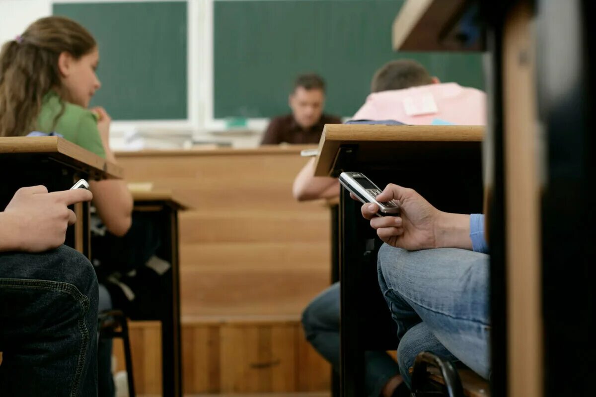 Беспалевно сидеть в телефоне на уроке. Списывает на уроке. ученик с телефоном на уроке. мобильник в школе. ученик списывает.