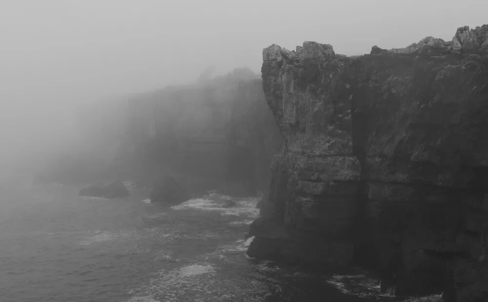 Берег ночью. Море скалы. Одинокий человек на скале. Обрыв туман. Обрыв темный.