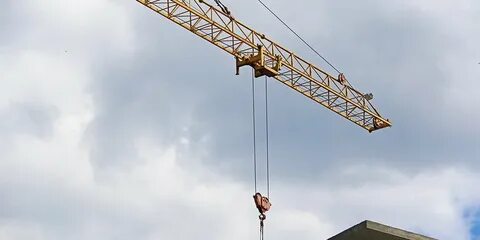 Башенный кран поднимает в горизонтальном положении балку